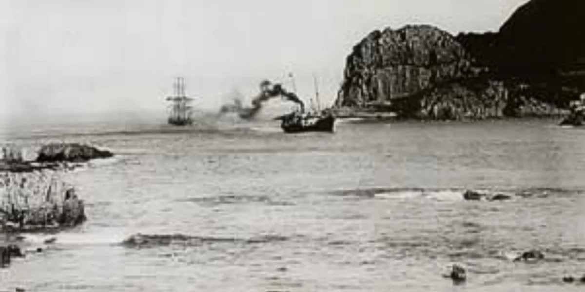 Black-and-white 1910 photograph of the Thesen-line steamship SS Agnar towing a sailing vessel through the Knysna Heads