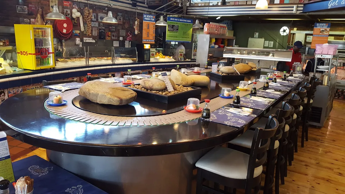 34 South Knysna Quays — sushi conveyor bar with stone serving trays and fresh fish counter behind