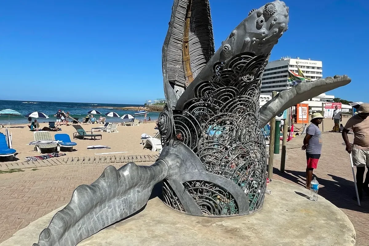 Bronze whale tail sculpture at Central Beach Plettenberg Bay, signalling the town's Whale Heritage Site status and the June–November whale-watching season