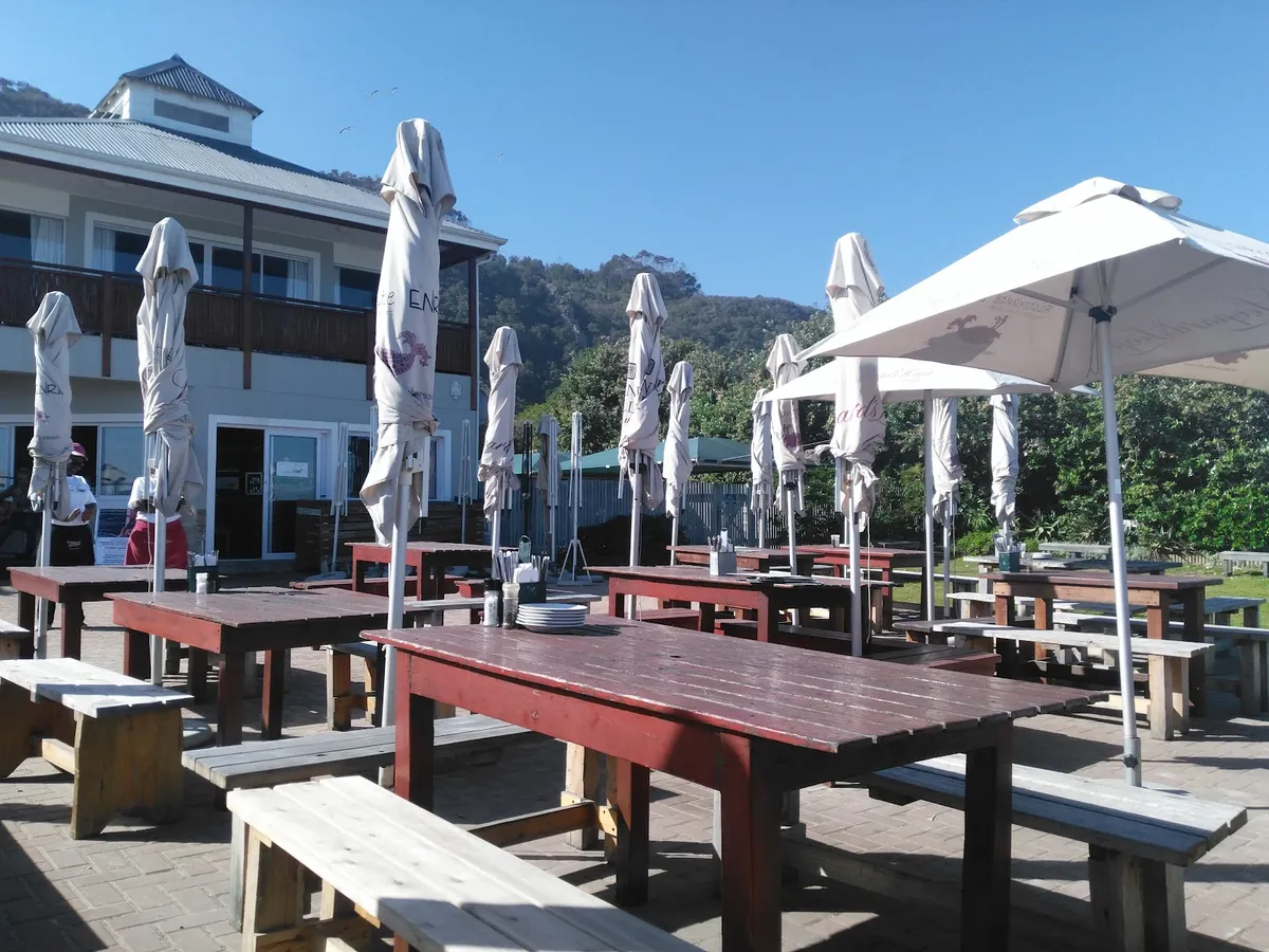 Enrico Ristorante outdoor terrace at Keurboomstrand — wooden tables and umbrellas with the restaurant building behind