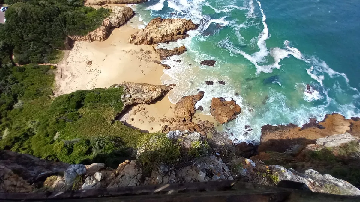 Knysna Heads at water level — sandstone cliffs towering over the lagoon entrance, white breakers on the rocks below