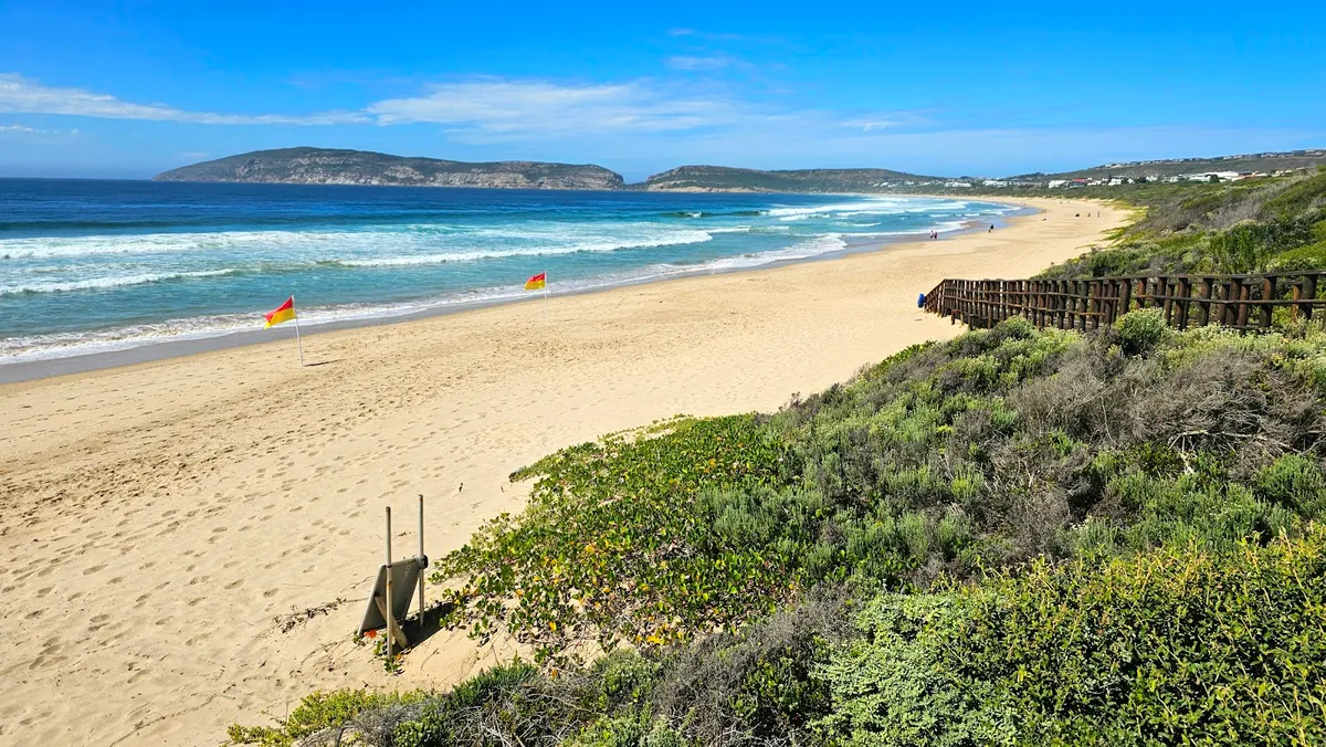 Robberg Beach Plettenberg Bay with red-yellow Blue Flag lifeguard flag, Robberg Peninsula on the horizon