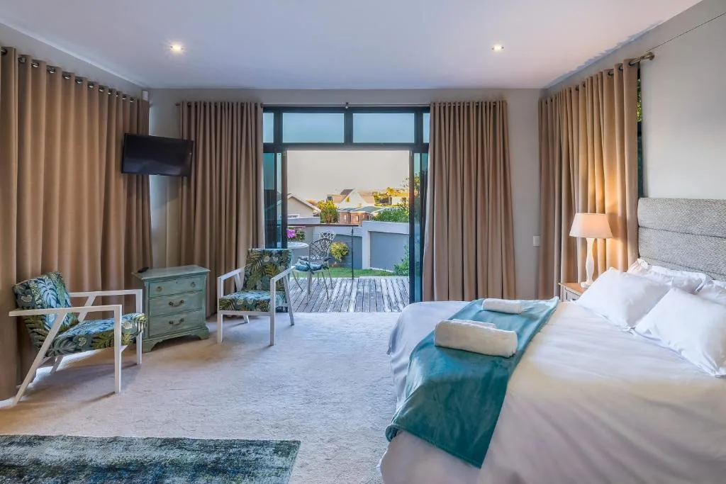 Spacious bedroom with king bed, lounge seating, and deck access overlooking garden