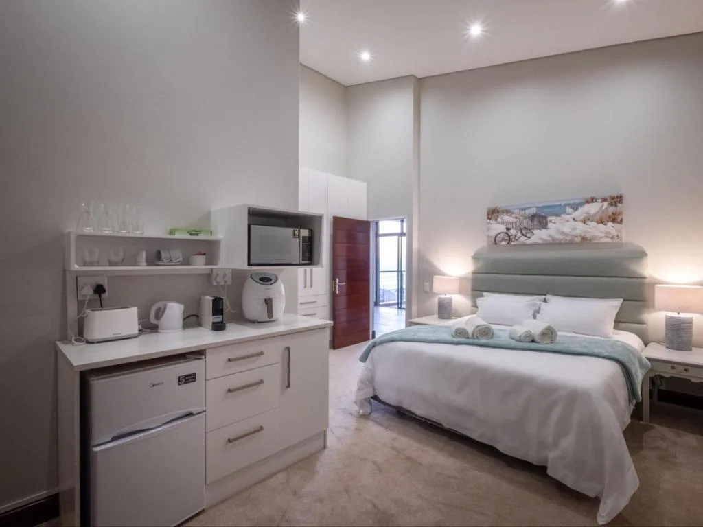 Modern bedroom with queen bed, en-suite kitchenette, and contemporary furnishings