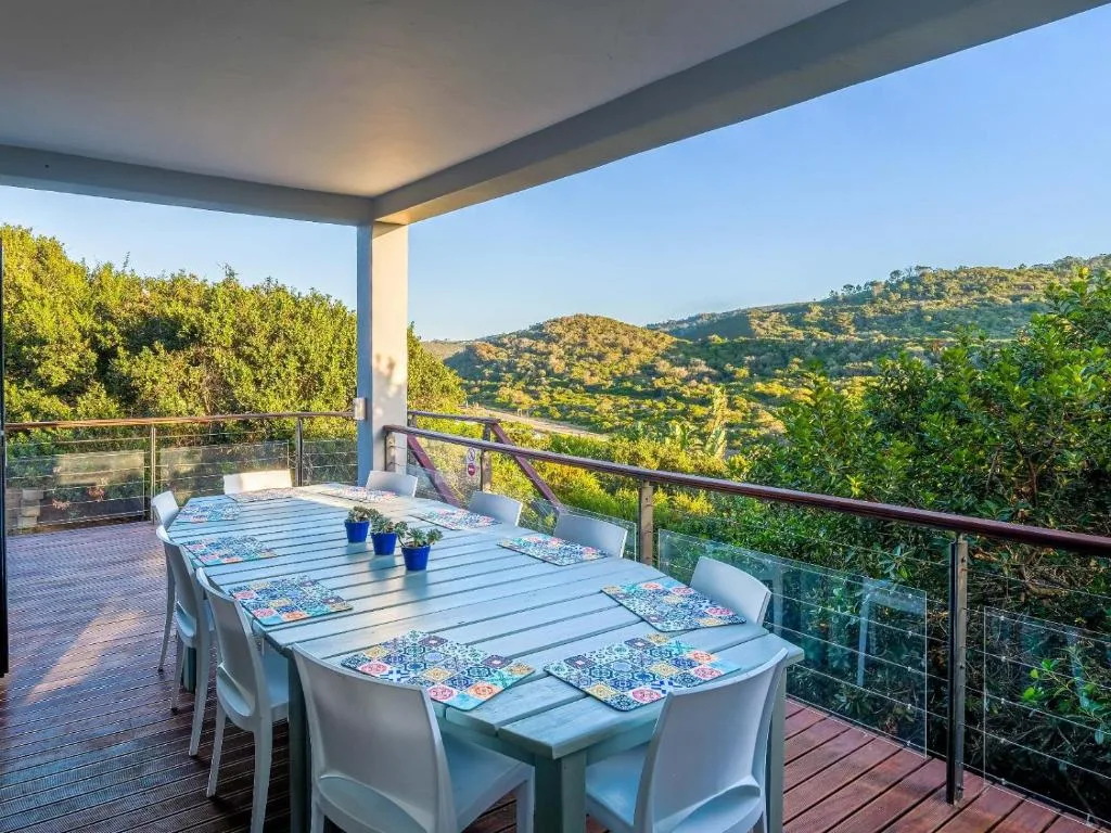 Covered deck with dining table overlooking forested hills and valley landscape