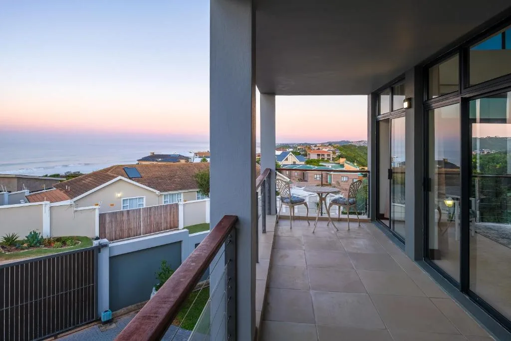 Spacious coastal deck with ocean views, seating area, and modern railings at sunset