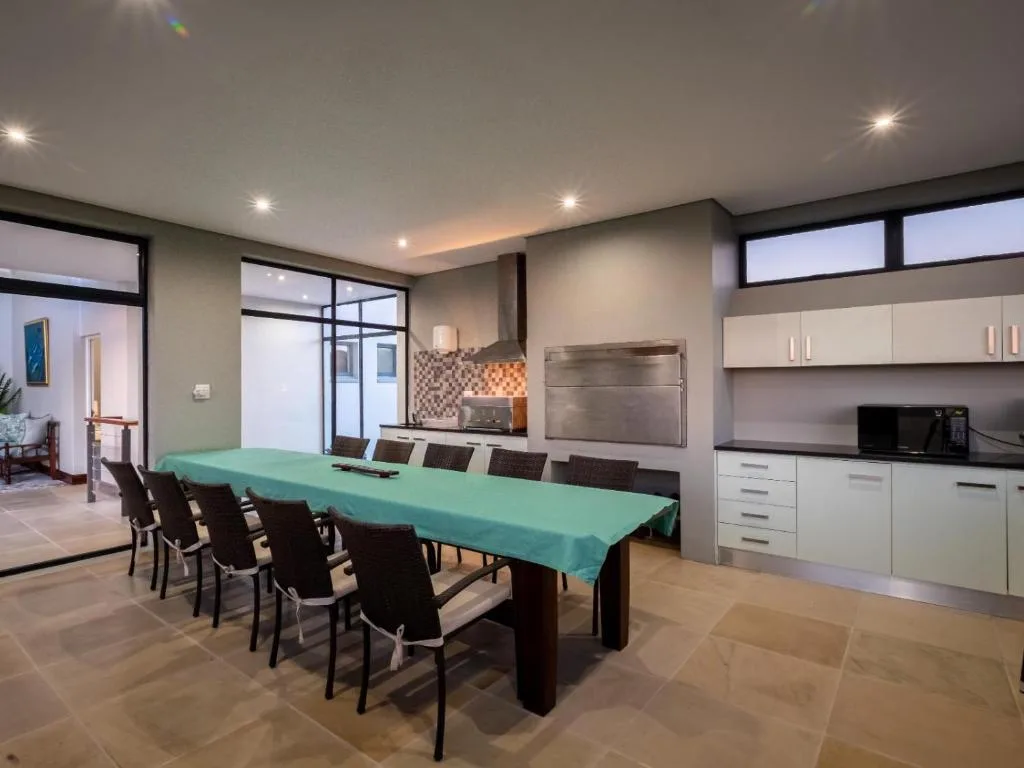 Modern dining area with turquoise tablecloth and dark chairs, adjoining kitchen