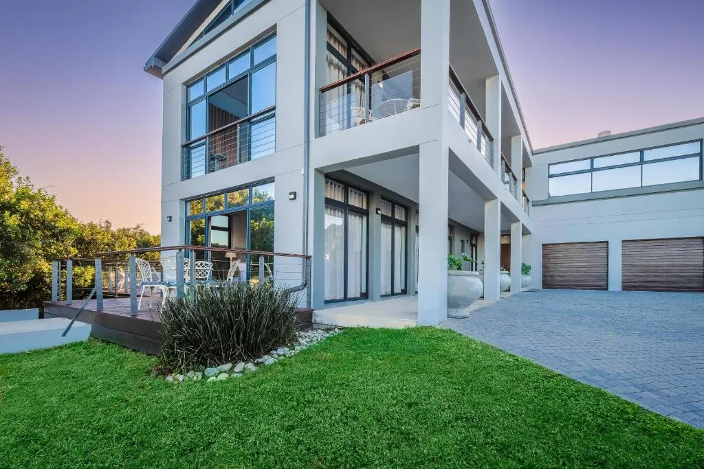 Modern white two-story house with manicured lawn and double garage at dusk