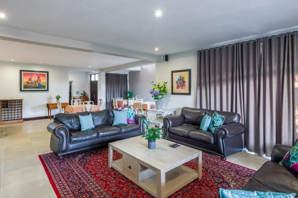 Spacious lounge with leather sofas, coffee table, and dining area beyond