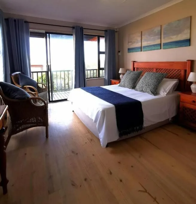 Spacious bedroom with ocean views through glass doors and balcony access
