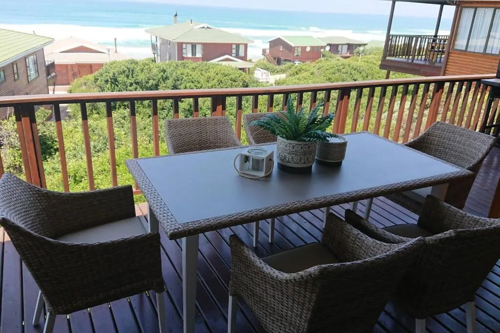 Ocean-view deck with wicker furniture and potted plants overlooking beach