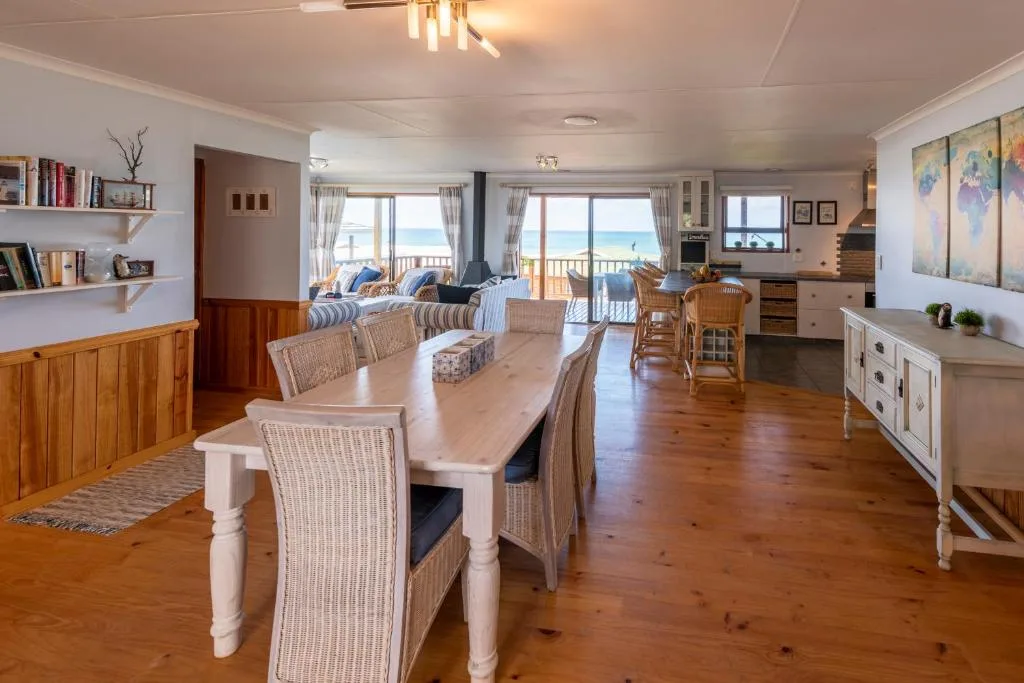 Spacious dining area with wooden table and woven chairs overlooking ocean