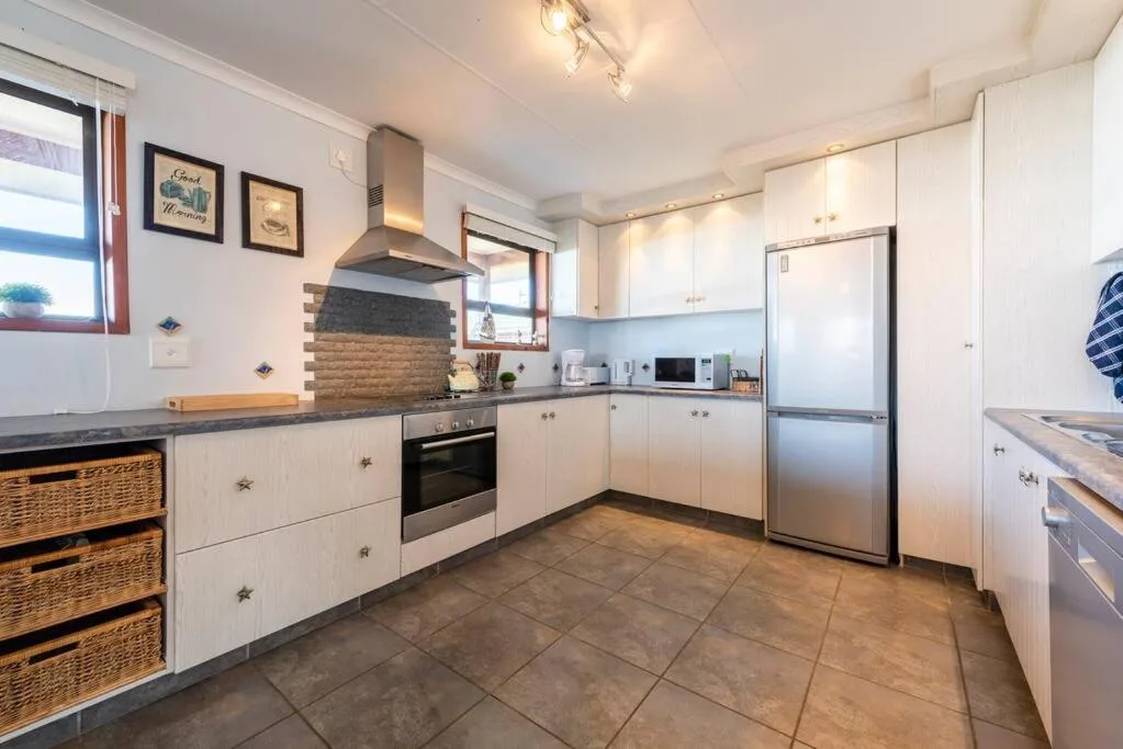 Modern kitchen with white cabinetry, stainless steel appliances, and brick feature wall