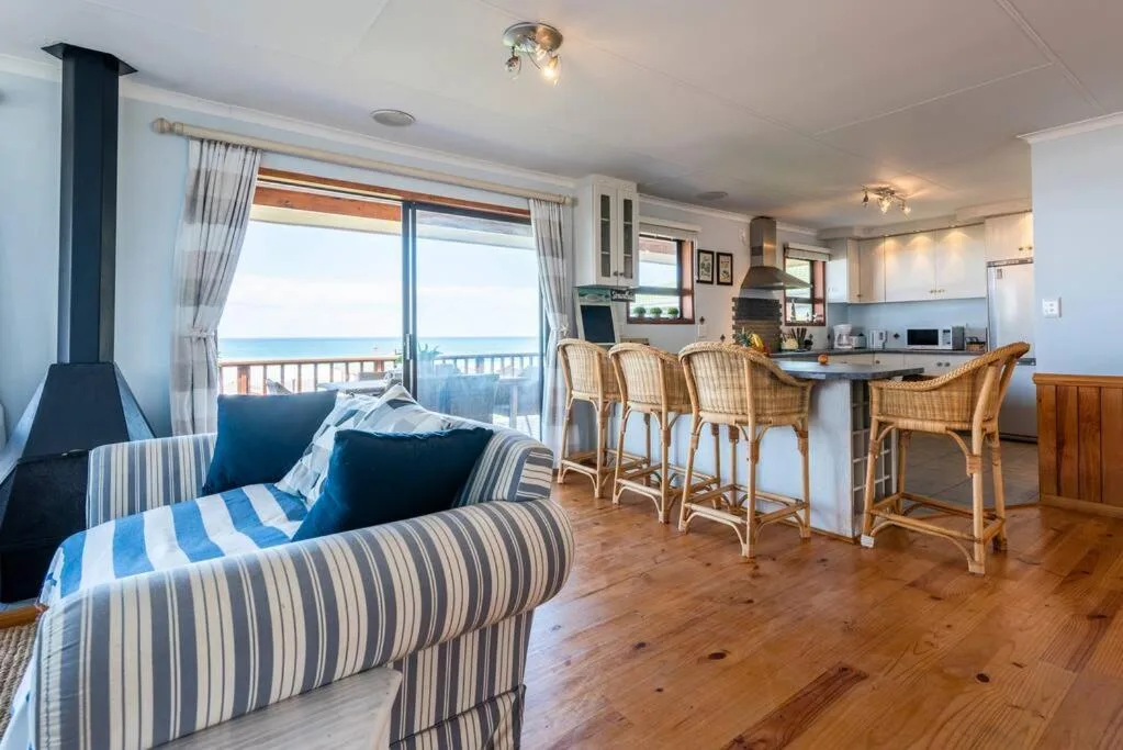 Spacious open-plan lounge with striped seating and ocean view through glass doors