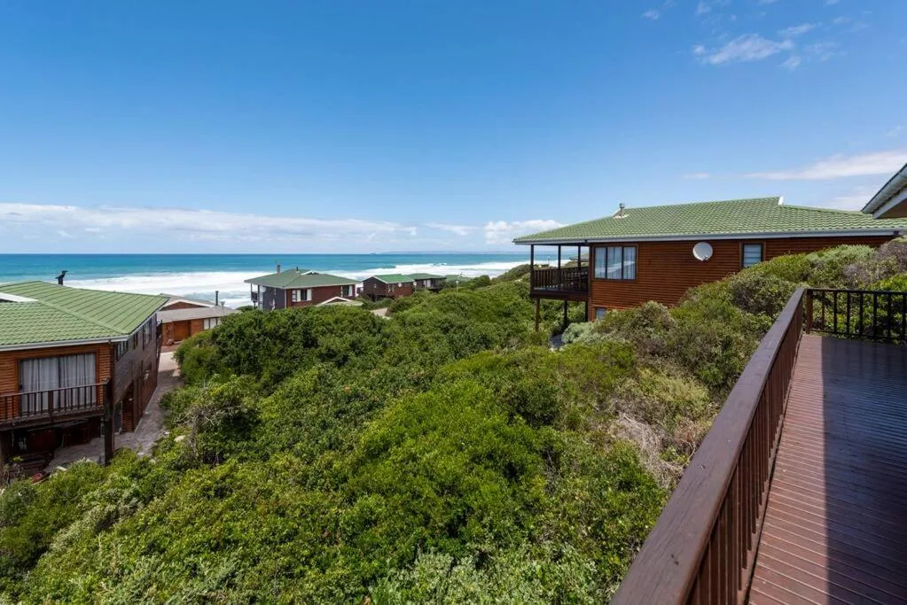 Ocean and beach vista from elevated coastal property with wooden decks