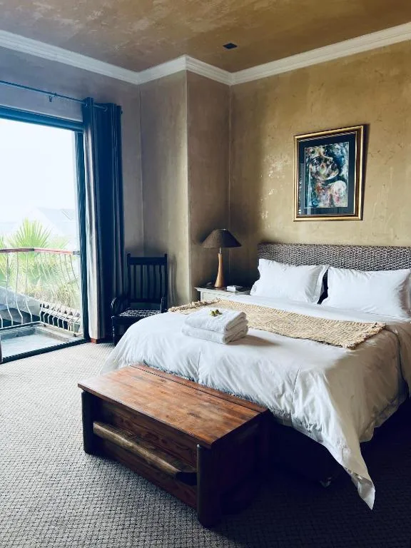 Spacious bedroom with queen bed, ocean view balcony, and coastal décor