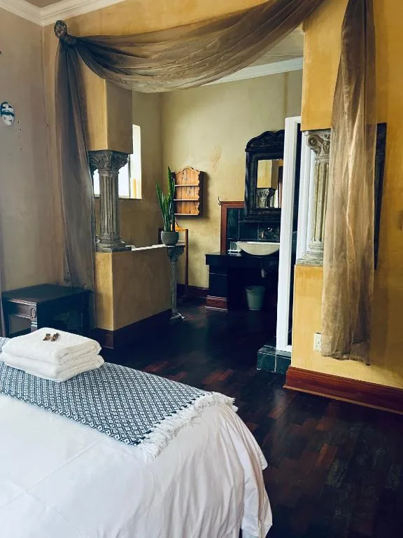 Bedroom with double bed, sheer curtains, and ensuite bathroom visible