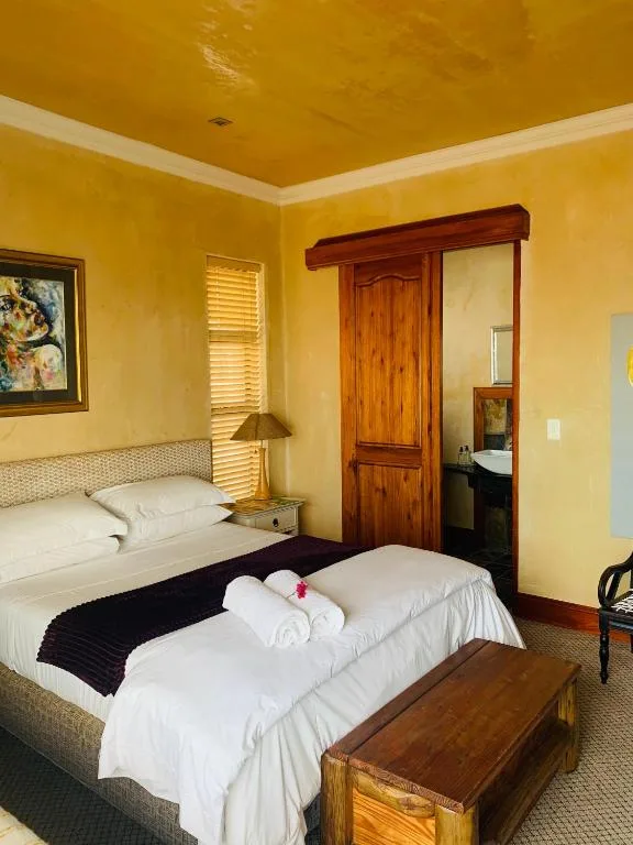 Bright yellow bedroom with two beds, wooden wardrobe, and ensuite bathroom