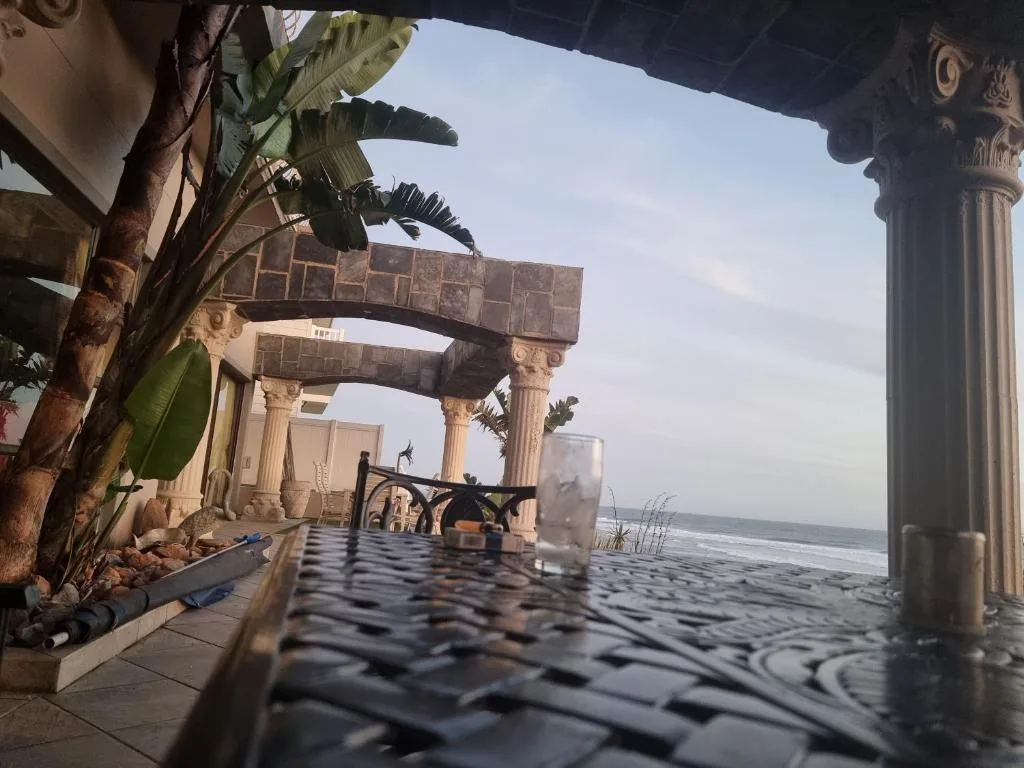 Covered beachfront patio with columns and ocean view beyond