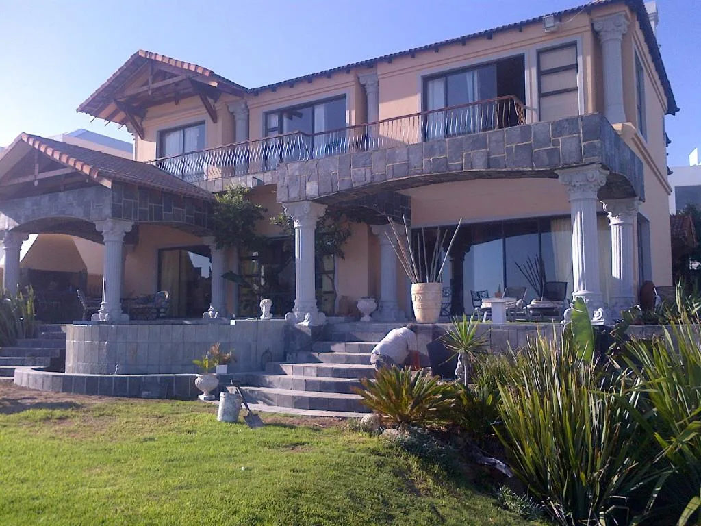 Elegant two-story beachfront house with stone columns and manicured gardens