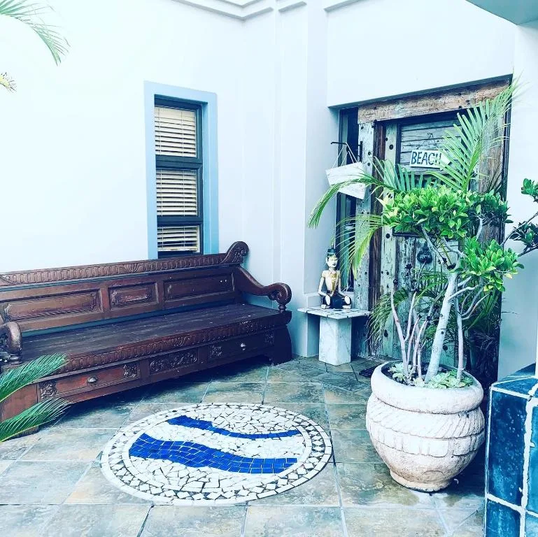 Coastal-themed entrance with wooden bench, potted plants, and mosaic floor