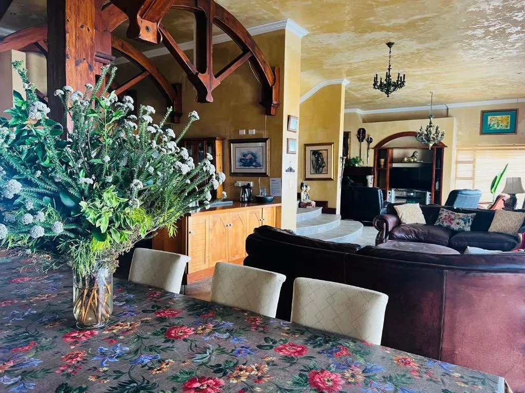 Spacious lounge with dark leather sofa, wooden beams, and floral arrangement