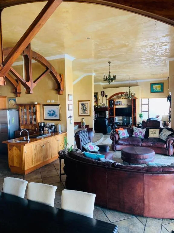 Open-plan lounge with burgundy sofa, high ceilings, wooden beams