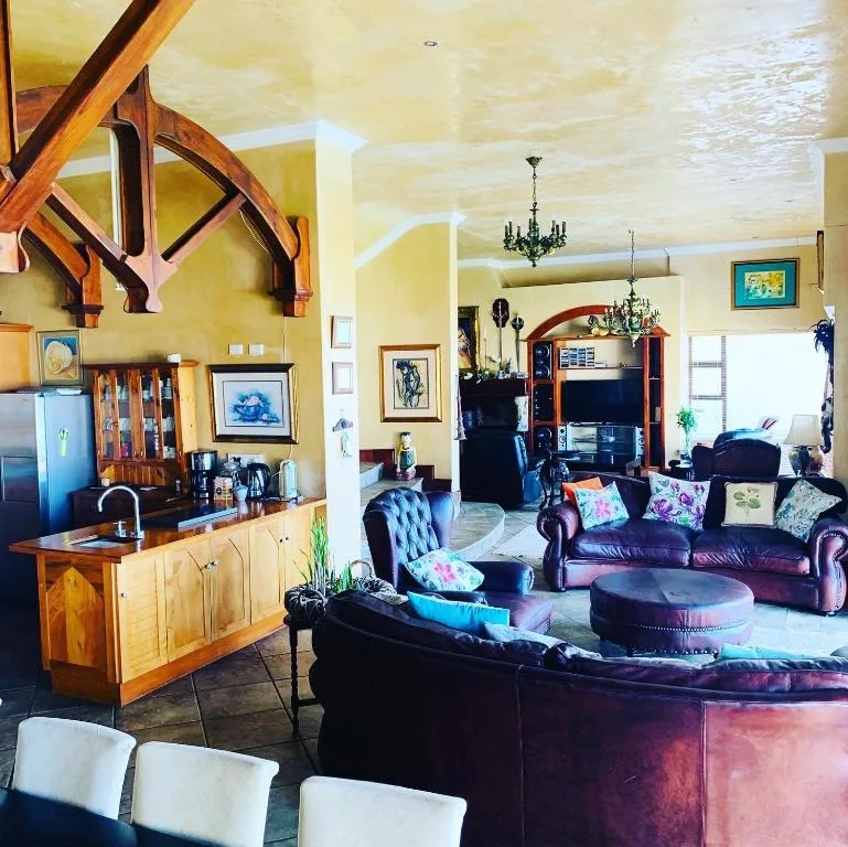 Open-plan lounge with purple leather sofas, wooden beams, and chandelier