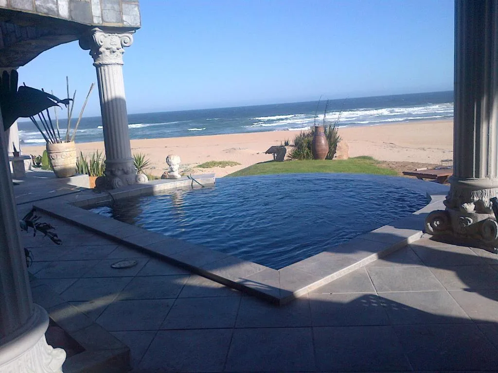 Beachfront infinity pool with ocean and sandy beach beyond