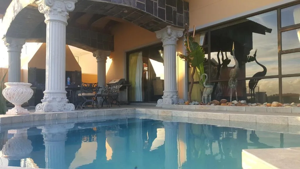 Swimming pool with classical columns and coastal sunset views