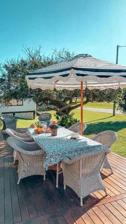 Shaded outdoor dining area with umbrella and wicker chairs on wooden deck