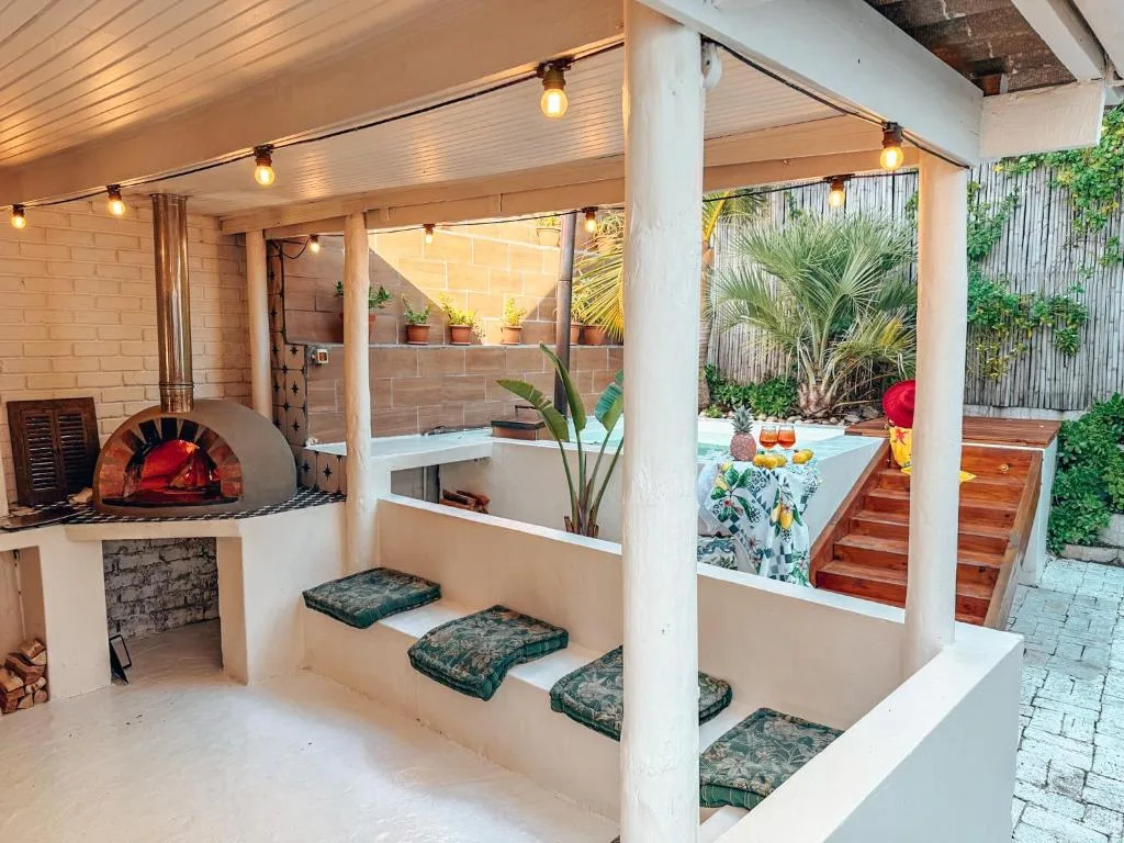 Covered outdoor entertainment area with pizza oven and seating overlooking pool