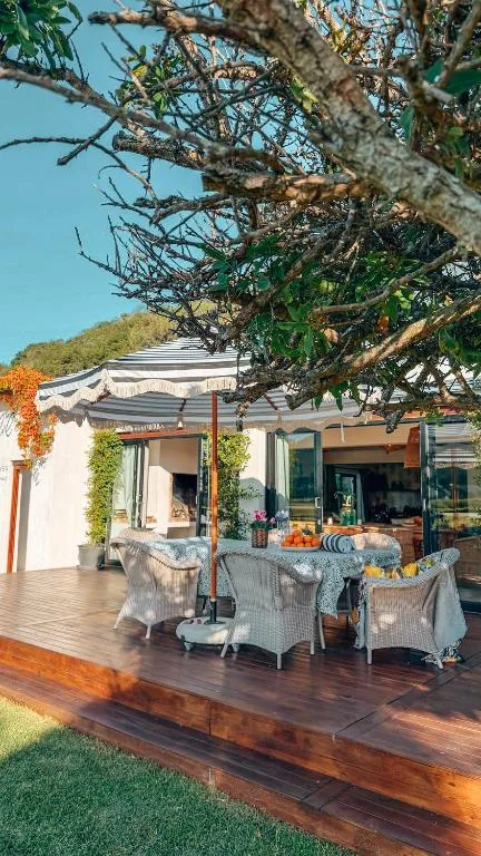 Wooden deck with outdoor seating and shade awning overlooking garden