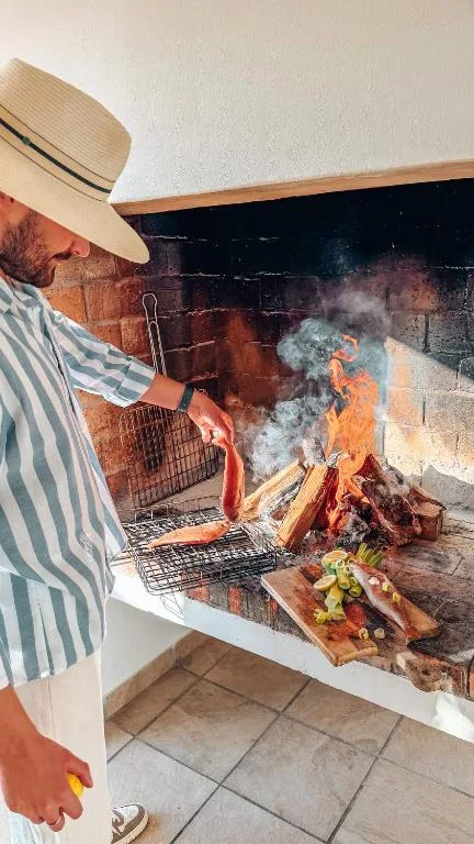 Man tending to outdoor braai fire with grilling meat and vegetables