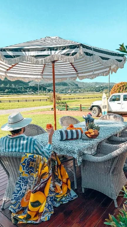 Shaded outdoor seating area with striped umbrella overlooking valley landscape