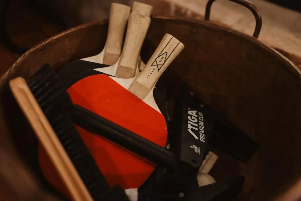 Table tennis paddles and ball nestled in wooden storage basket