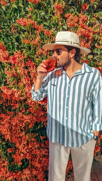 Man enjoying fresh watermelon against vibrant red flowering vines backdrop