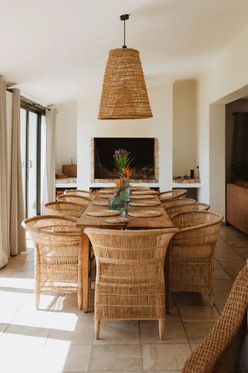 Dining area with woven rattan chairs around wooden table and fireplace