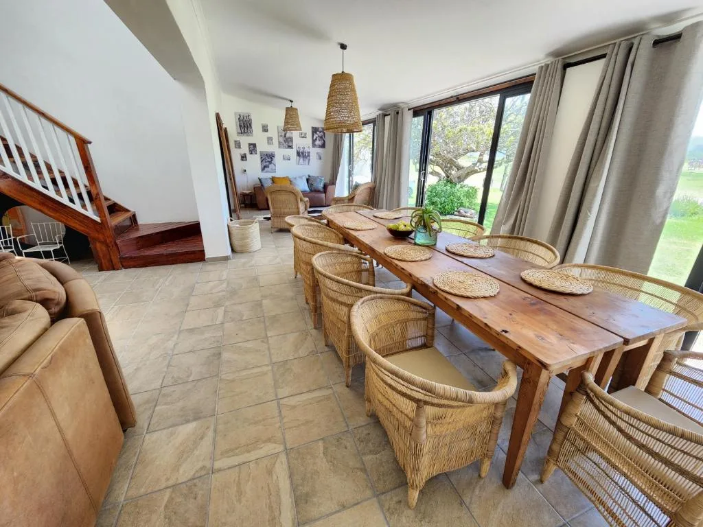 Open-plan dining area with wooden table and woven rattan chairs