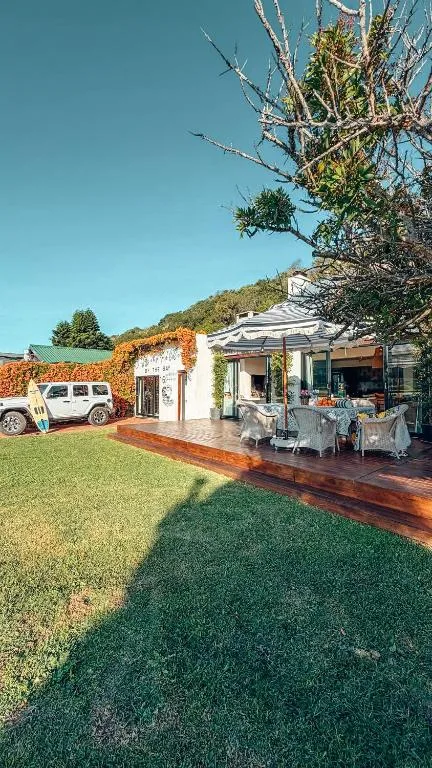 Modern white cottage with striped awning and manicured lawn overlooking hills