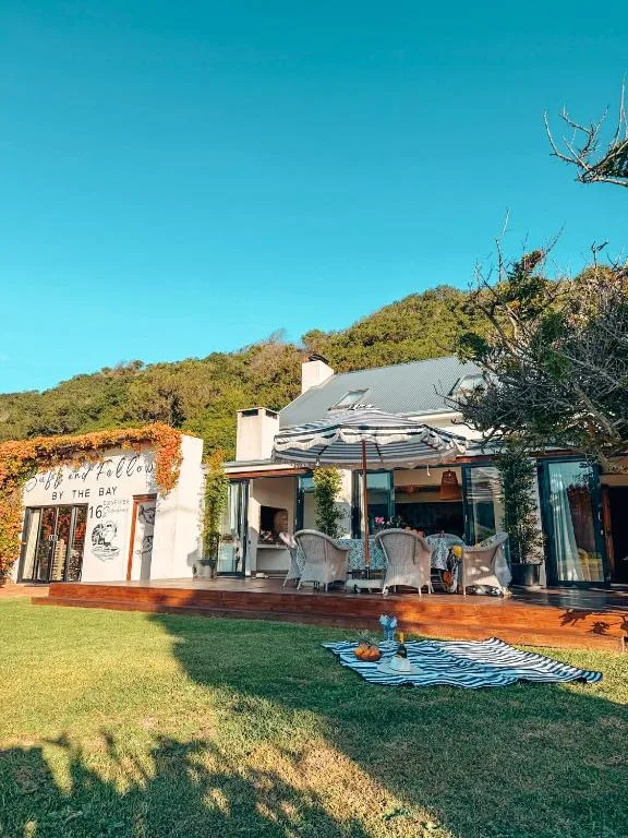 White cottage with deck nestled against lush green hillside landscape