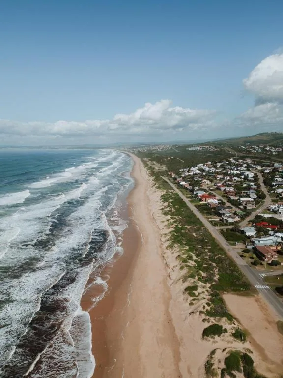 Aerial view of pristine sandy beach with crashing waves and coastal town