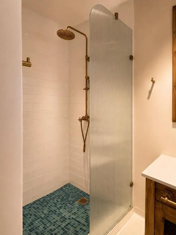 Modern shower enclosure with brass fixtures and rainfall showerhead