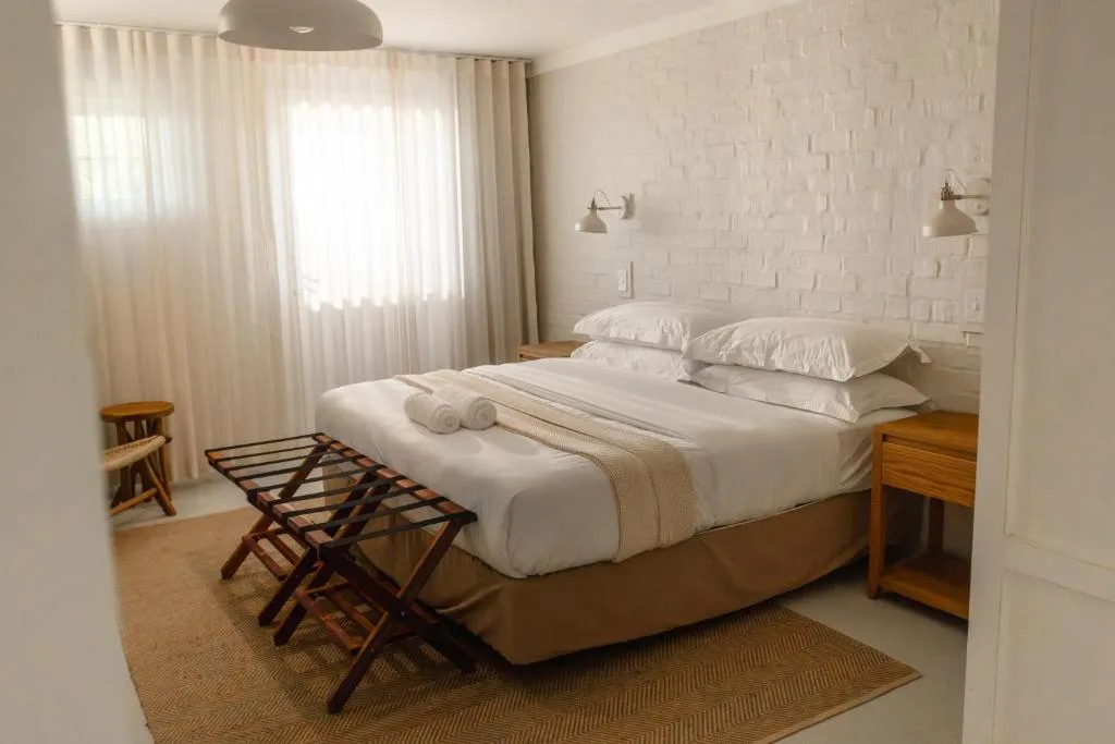 Bright bedroom with crisp white bedding and wooden nightstands beside large windows