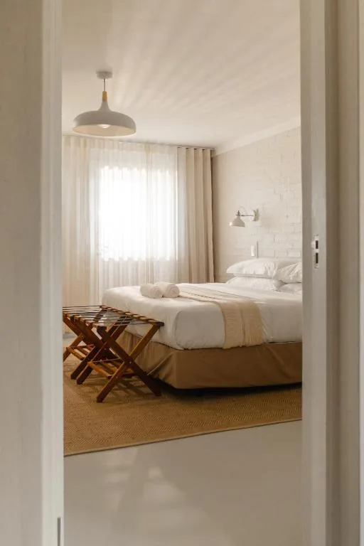 Bright bedroom with white bed, pendant light, and natural window views