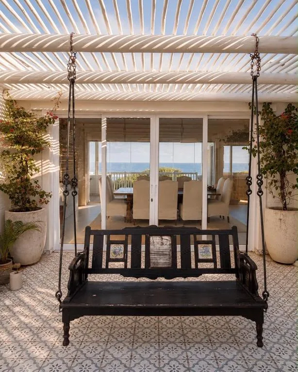 Shaded outdoor patio with hanging bench and sea view access