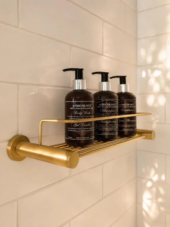 Brass bathroom shelf with natural product bottles and toiletries
