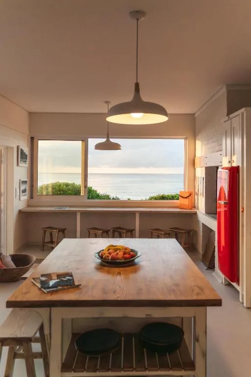 Modern dining table with ocean view through large windows, pendant lighting overhead
