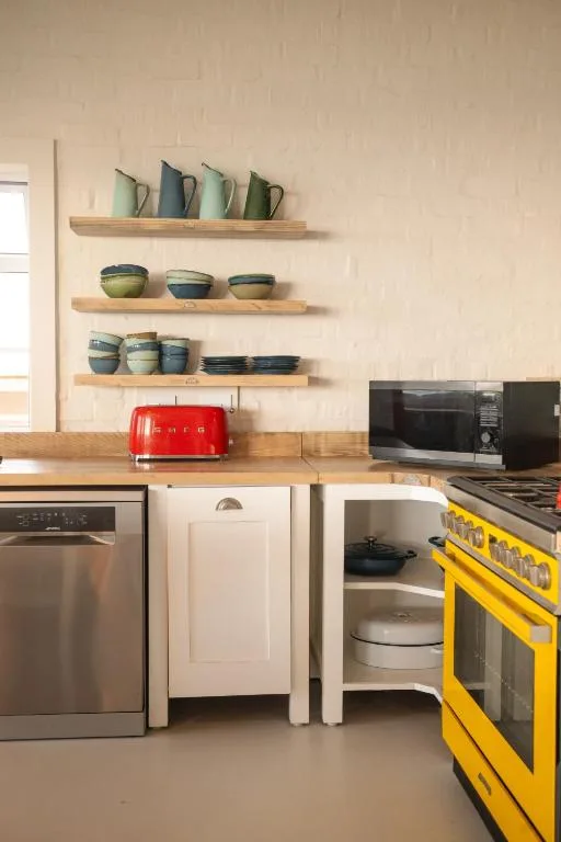 Modern kitchen with wooden shelves displaying ceramic dishware and appliances