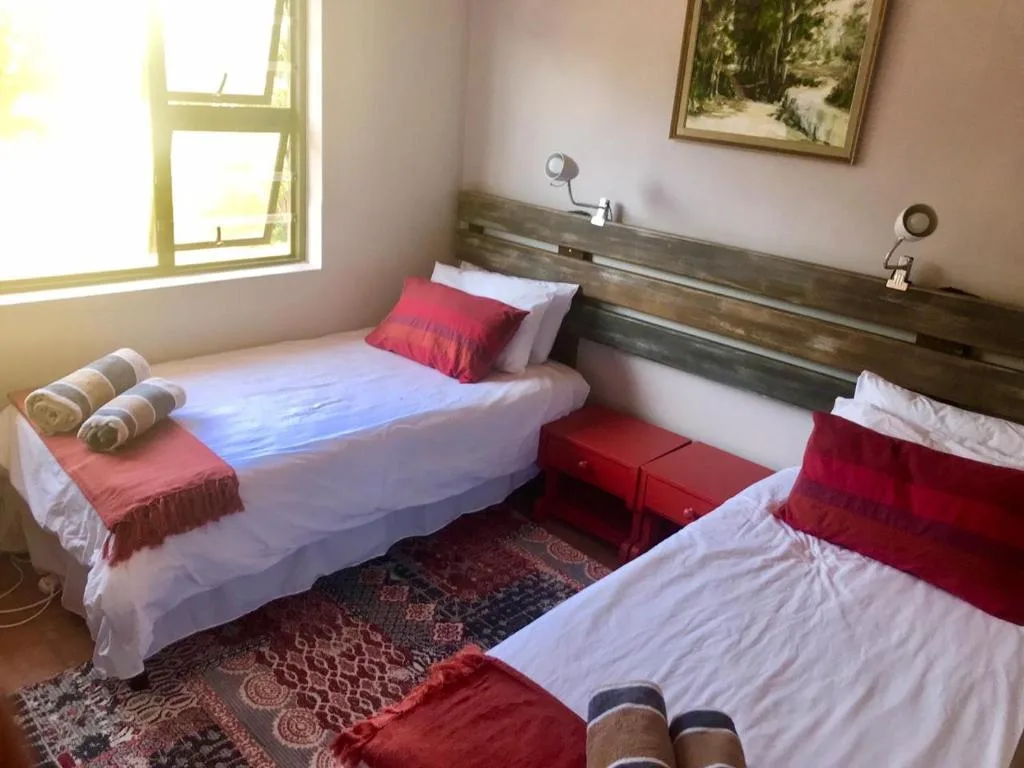 Bright bedroom with two single beds, red accents, and natural light from window